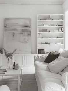 a black and white photo of a living room with bookshelf in the background