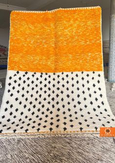 an orange and white blanket with black crosses on it, sitting on top of a carpet