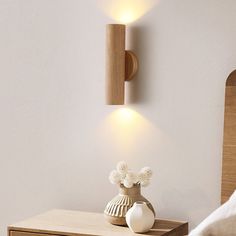 a bedroom scene with focus on the bedside table and wall sconces, which are mounted to the wall