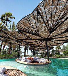 an outdoor swimming area with umbrellas and pillows