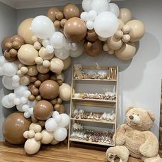 a teddy bear sitting in front of a display of balloons and desserts on shelves