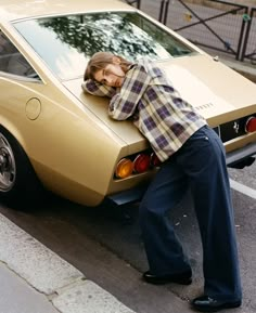 a man leaning on the hood of a car with his head resting on it's trunk