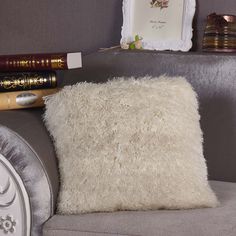 a white pillow sitting on top of a gray couch next to a mirror and pen