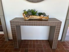 a clock on the wall next to a table with succulents in it