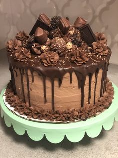 a cake with chocolate icing and decorations on top is sitting on a green platter