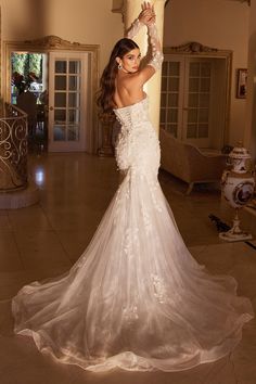 a woman in a white wedding dress posing for the camera with her arms up and hands behind her head