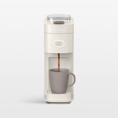 a white coffee maker with a cup in it