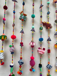 colorful beaded necklaces are hanging on a white wall with other beads and decorations