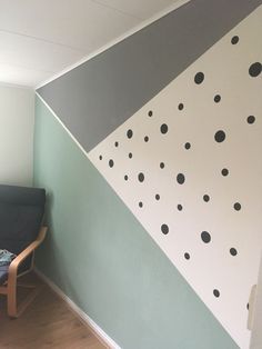 a chair sitting in front of a wall painted with black and white polka dot designs