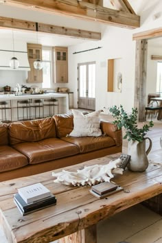 A cozy and inviting rustic living room featuring a leather couch, wooden beams, and farmhouse decor essentials for a homey feel. Leather Farmhouse Living Room, Modern Farmhouse Living Room With Leather Furniture, Rustic Living Room Leather Couch, Modern Farmhouse Living Room And Kitchen, Natural Farmhouse Living Room, Farmhouse Rustic Decor Living Room, Living Room Inspiration With Leather Couch, Charming Apartment Decor, Modern Farmhouse Leather Couch