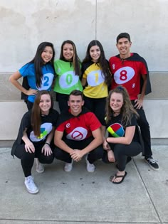 a group of young people posing for a photo in front of a building with numbers on their shirts