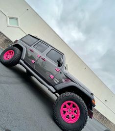 a gray truck with pink wheels parked in front of a building