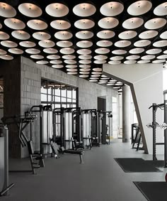 an empty gym with rows of exercise machines and treadmills in the center, surrounded by round lights