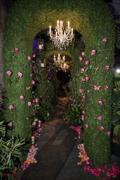 an archway covered in flowers and greenery with chandelier