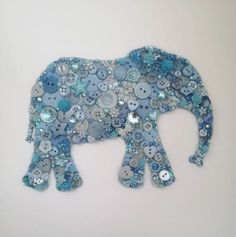 an elephant made out of buttons on a white wall with blue and silver sequins