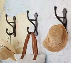 two hats are hanging on the wall next to a map and hooks for hat holders