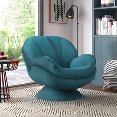 a blue chair sitting on top of a rug in a living room next to a book shelf