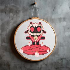 a cross stitch pattern hanging on a wall with a wooden hoop holding it in the shape of a cartoon character