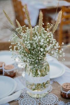 a vase filled with baby's breath sitting on top of a table next to plates