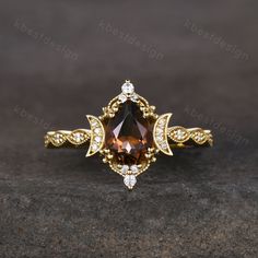 an engagement ring with a large brown stone surrounded by white and yellow diamonds on a dark surface