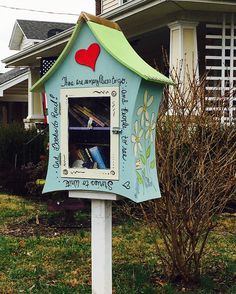 a blue birdhouse with a red heart painted on it's side in front of a house