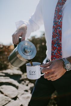 a man in a tie is pouring coffee into a cup with the word g v on it