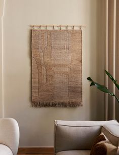 a living room with two chairs and a rug hanging on the wall