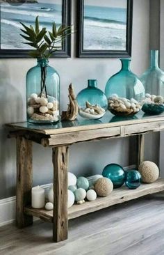 a table with vases and shells on it in front of two framed pictures above it