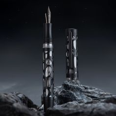 two pens sitting on top of a rock next to each other in the dark sky