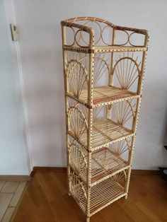 a three tier bamboo shelf with wheels on the top and bottom, in front of a wall