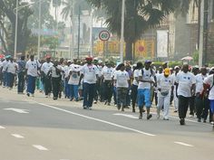 a large group of people are walking down the street in front of some palm trees