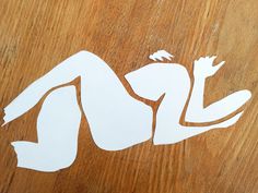 a wooden table topped with cut outs of a naked woman sitting on top of it