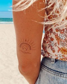 a woman's arm with a sun and wave tattoo on the left side of her right arm