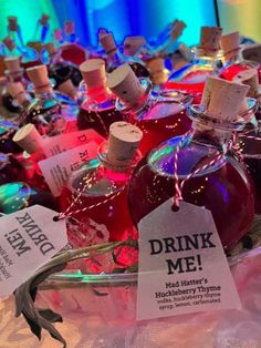 several bottles of alcohol are on display with tags attached to the bottle caps that say drink me