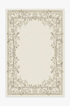 a white and beige rug with an ornate border on the bottom, surrounded by flowers