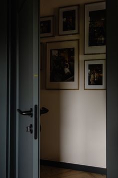 an open door with pictures hanging on the wall and wood flooring in front of it