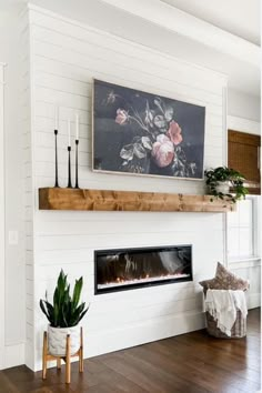 a living room with white walls and wood floors, a fireplace mantel and a painting on the wall