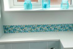 a window sill with blue glass bottles on it and a sink in the corner