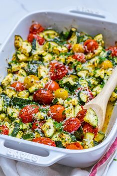 a casserole dish with tomatoes, zucchini and spinach in it