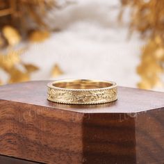 a gold wedding band sitting on top of a wooden box