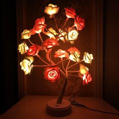 a lamp that is on top of a table with flowers lit up in the dark