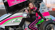 a woman sitting on top of a pink and green race car