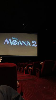 people sitting on red chairs in front of a large screen with the words moan 2