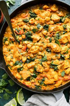 a skillet filled with chicken and spinach in a creamy, yellow curry sauce