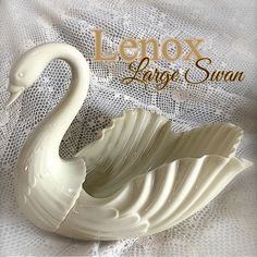 a white swan shaped bowl sitting on top of a bed next to the words lenox large swan