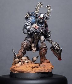 a miniature warhammer with skulls and bones on it's head, holding a large knife