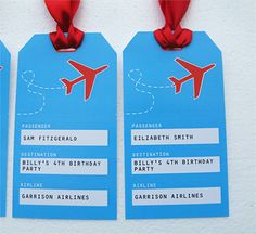 two blue luggage tags with red ribbons attached to them, one has an airplane on it