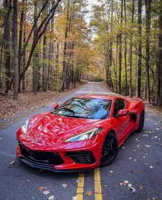 a red sports car parked on the side of a road in front of some trees