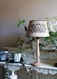 a lamp sitting on top of a white table next to a vase and potted plant