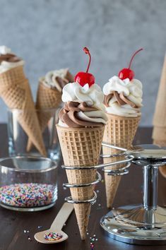 three ice cream cones with chocolate frosting, sprinkles and cherries